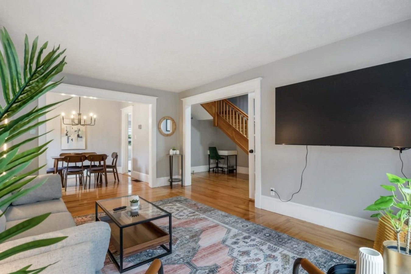 A spacious living room with a sofa, coffee table, and a large flat-screen TV mounted on the wall.