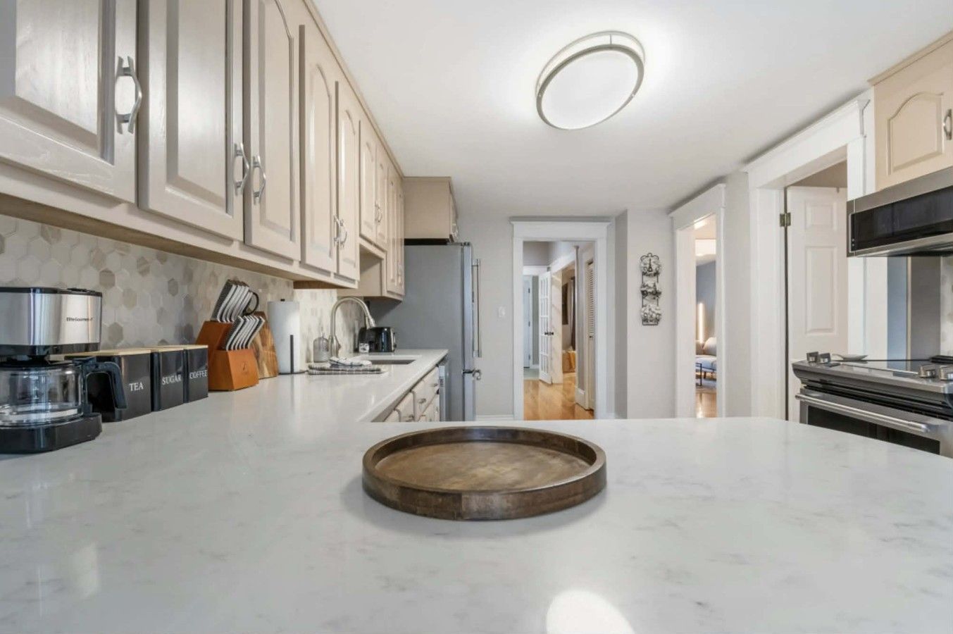 A modern kitchen with a marble countertop, a coffee machine, and cabinets.
