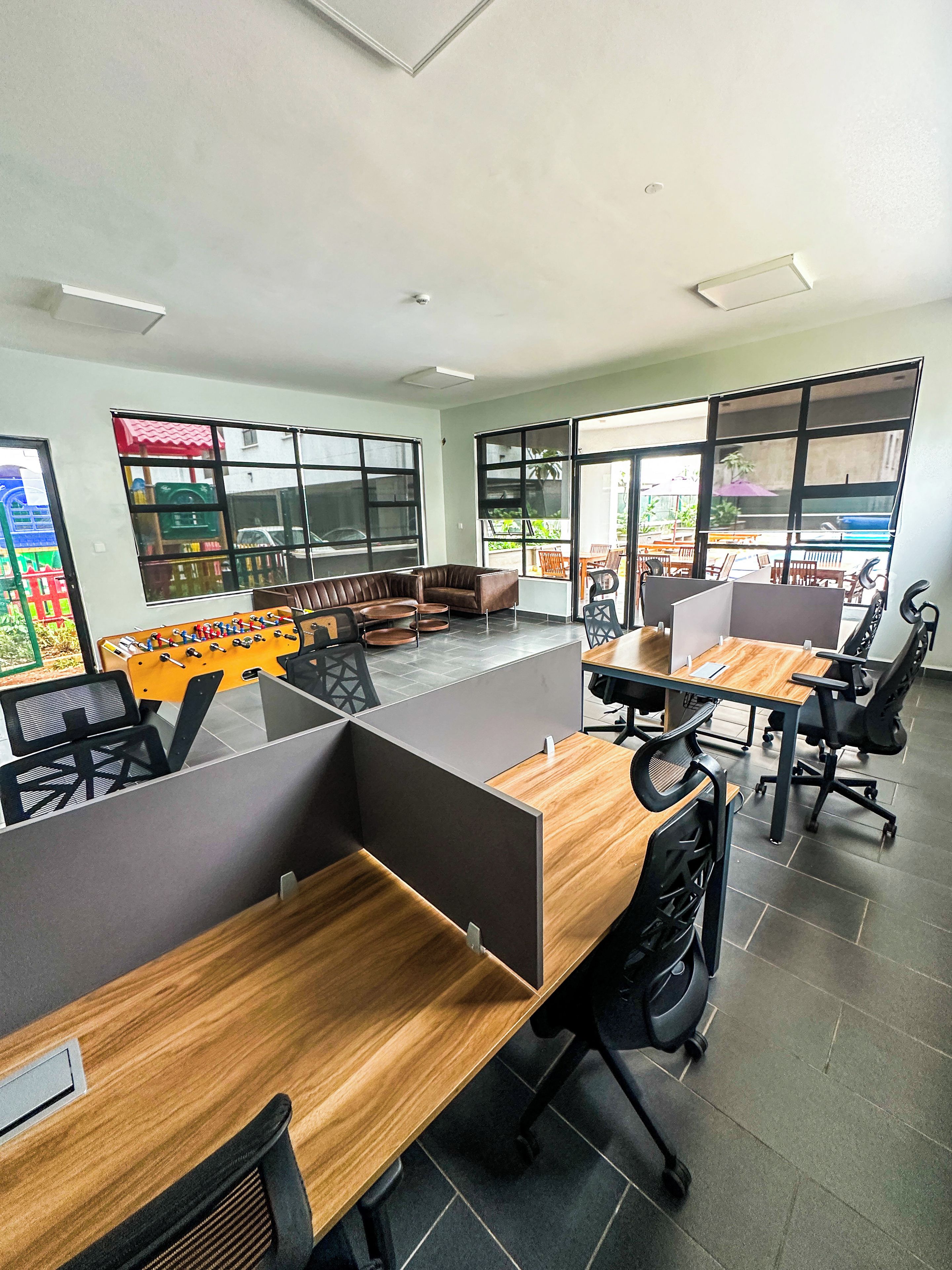 A modern office space with cubicles, a foosball table, and large windows.