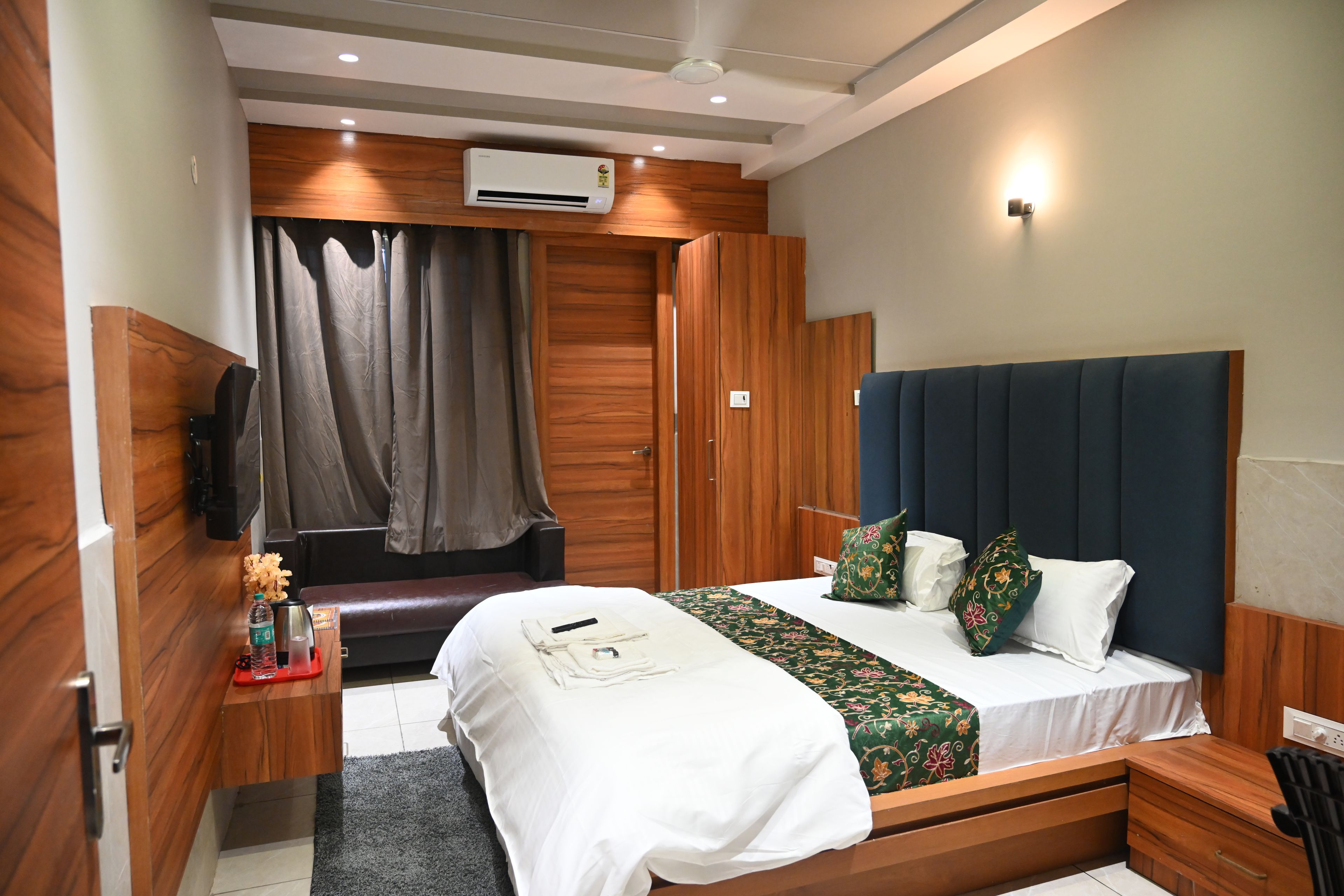 A hotel room with a bed, bedside table, and a wardrobe.