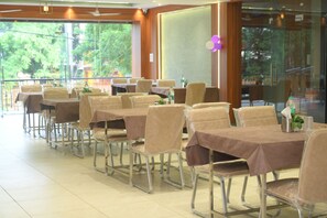 A restaurant with tables covered in brown tablecloths and chairs with plastic seat covers.