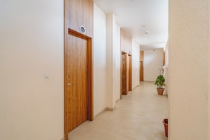 Un couloir avec des portes en bois, une plante en pot et un sol carrelé.