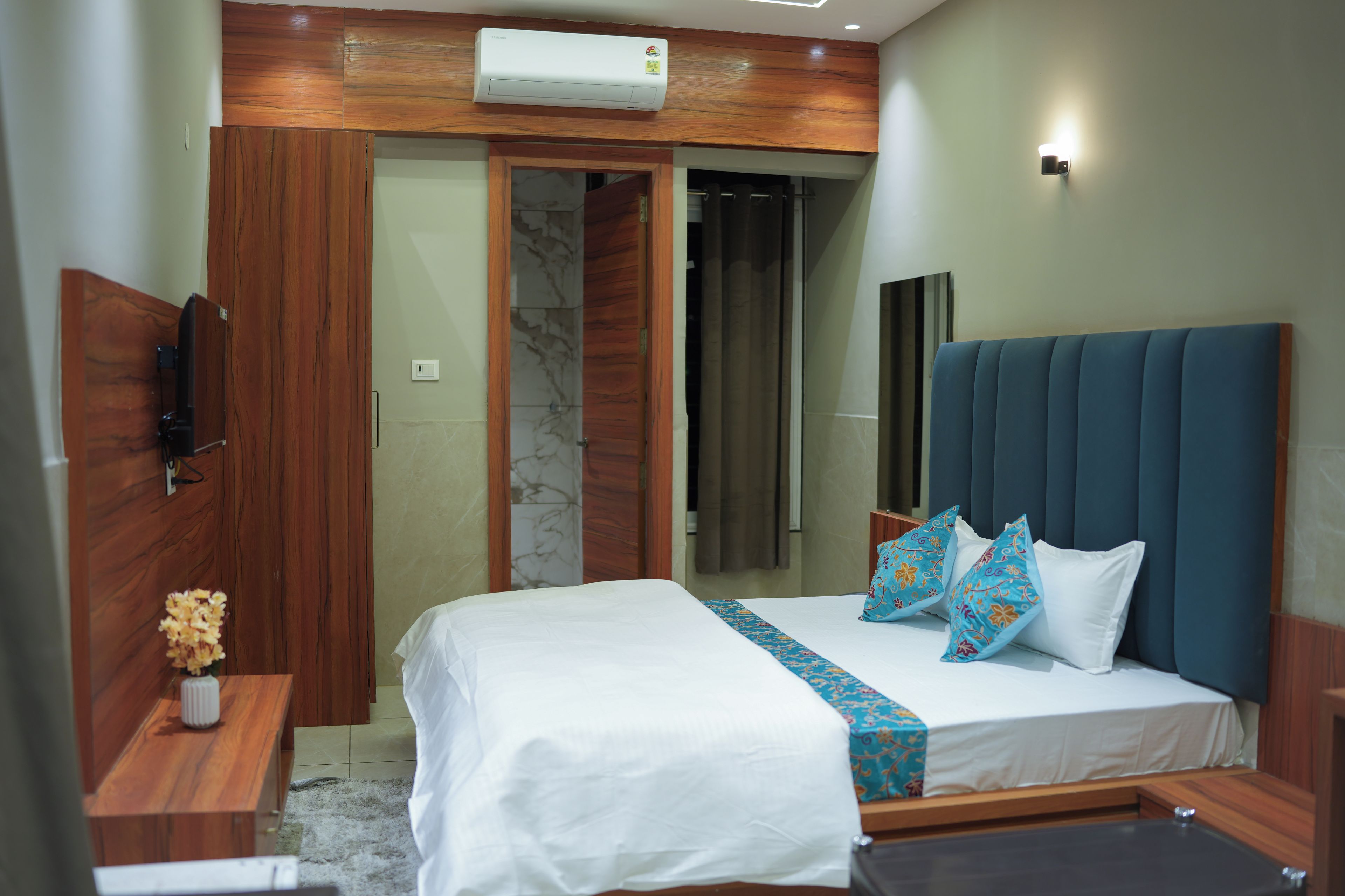 Una habitación de hotel con cama, mesita de noche, espejo y armario.