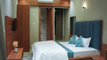 Una habitación de hotel con cama, mesita de noche, espejo y armario.