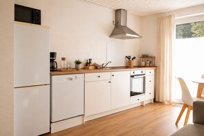 Eine moderne Küche mit weißen Schränken, einer Edelstahl-Dunstabzugshaube, einem Einbauofen und einer Kaffeemaschine.