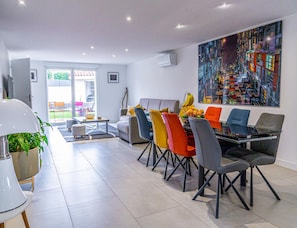 Uma sala de jantar moderna com uma mesa posta para quatro pessoas, rodeada por cadeiras coloridas.