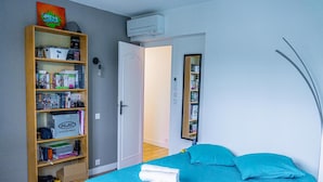 Un dormitorio con cama, una estantería, una puerta y un espejo.