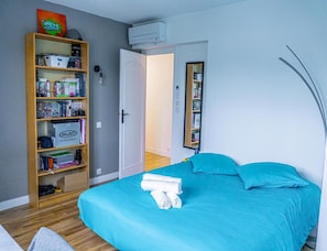 Quarto com cama, estante, porta e espelho.