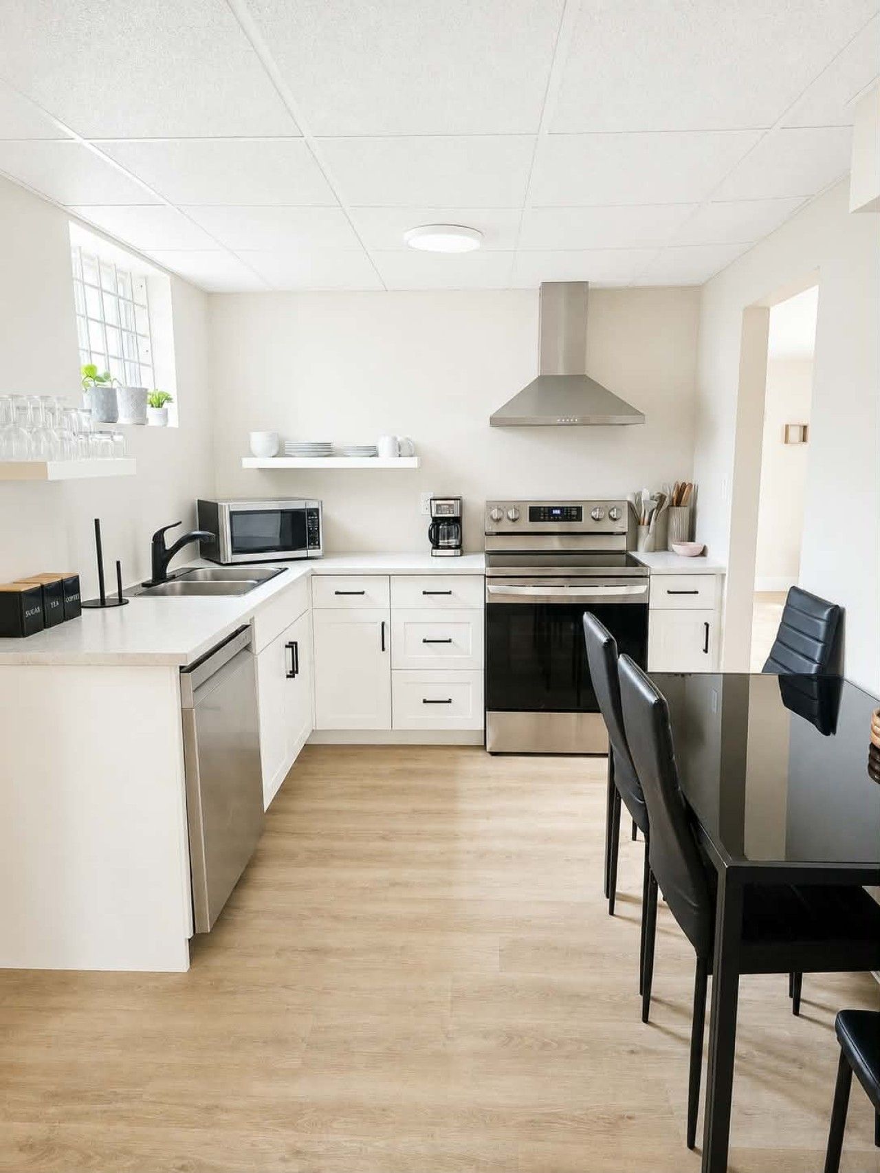 Een moderne keuken met witte kasten, een roestvrijstalen fornuis, een magnetron en een koffiezetapparaat.