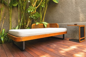 A wooden bed with a mattress, a wooden headboard, and a small wooden table with a bowl on top. - Villa Daksa Ubud by Tasvan (Gianyar)