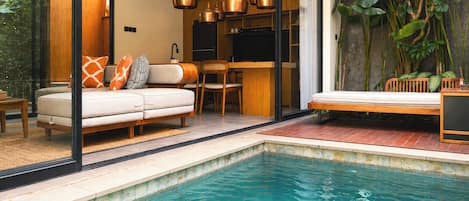 Un intérieur moderne avec une piscine, un ensemble de canapés et un coin repas.