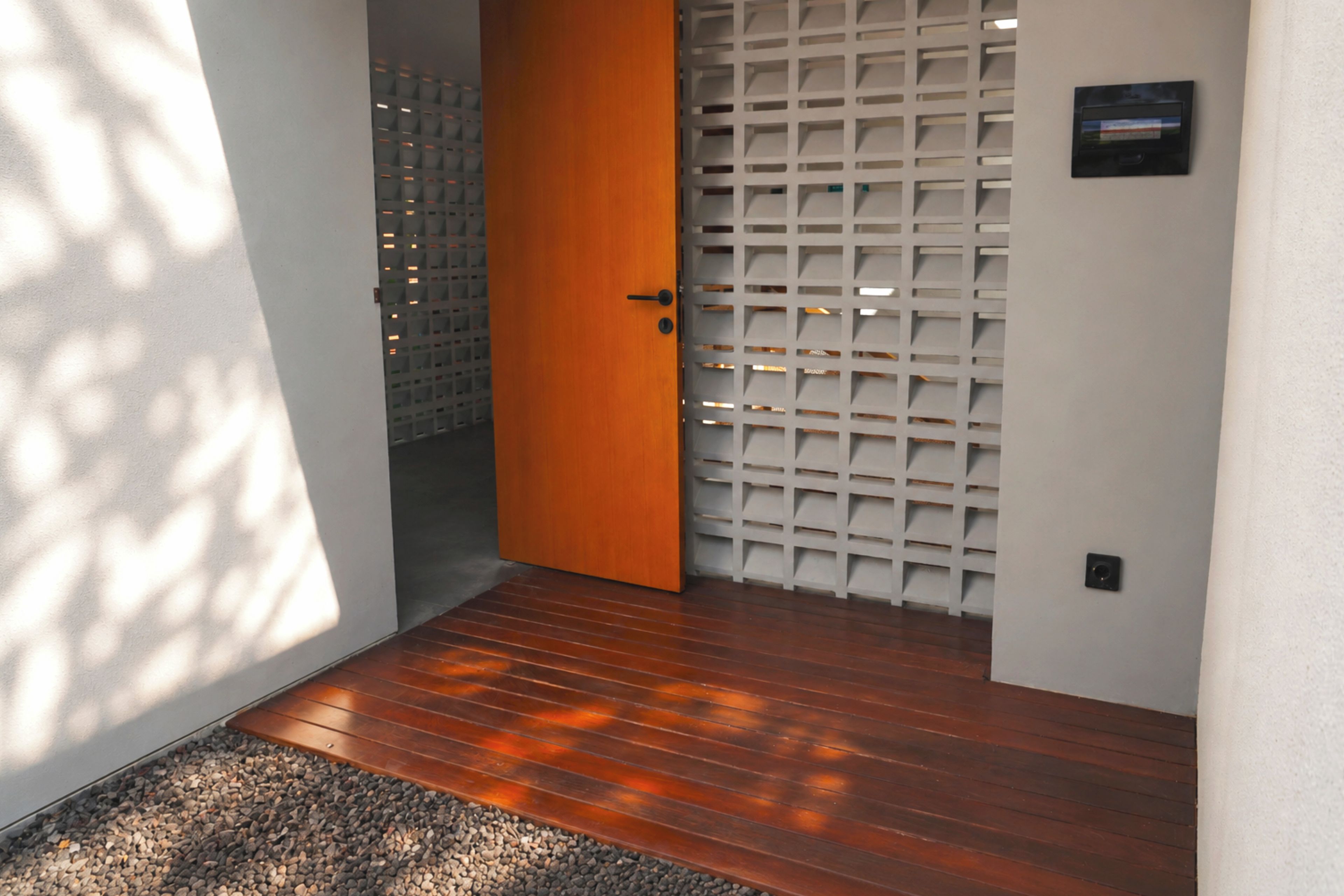 A wooden floor leading to a door with a white lattice panel.