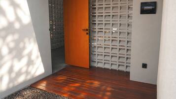 A wooden floor leading to a door with a white lattice panel.