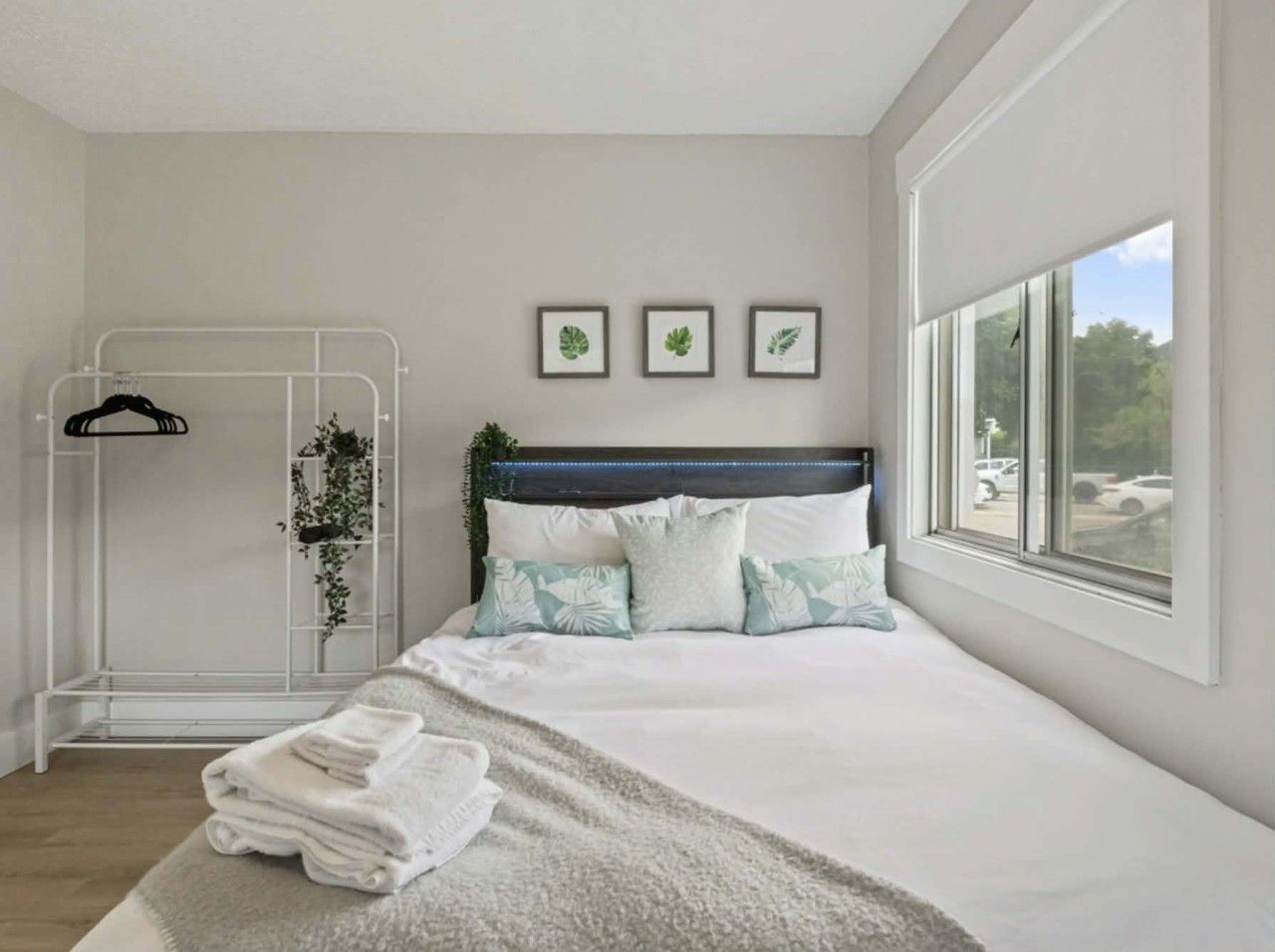 A bedroom with a bed, a window, a shower area, and a wall with framed pictures.