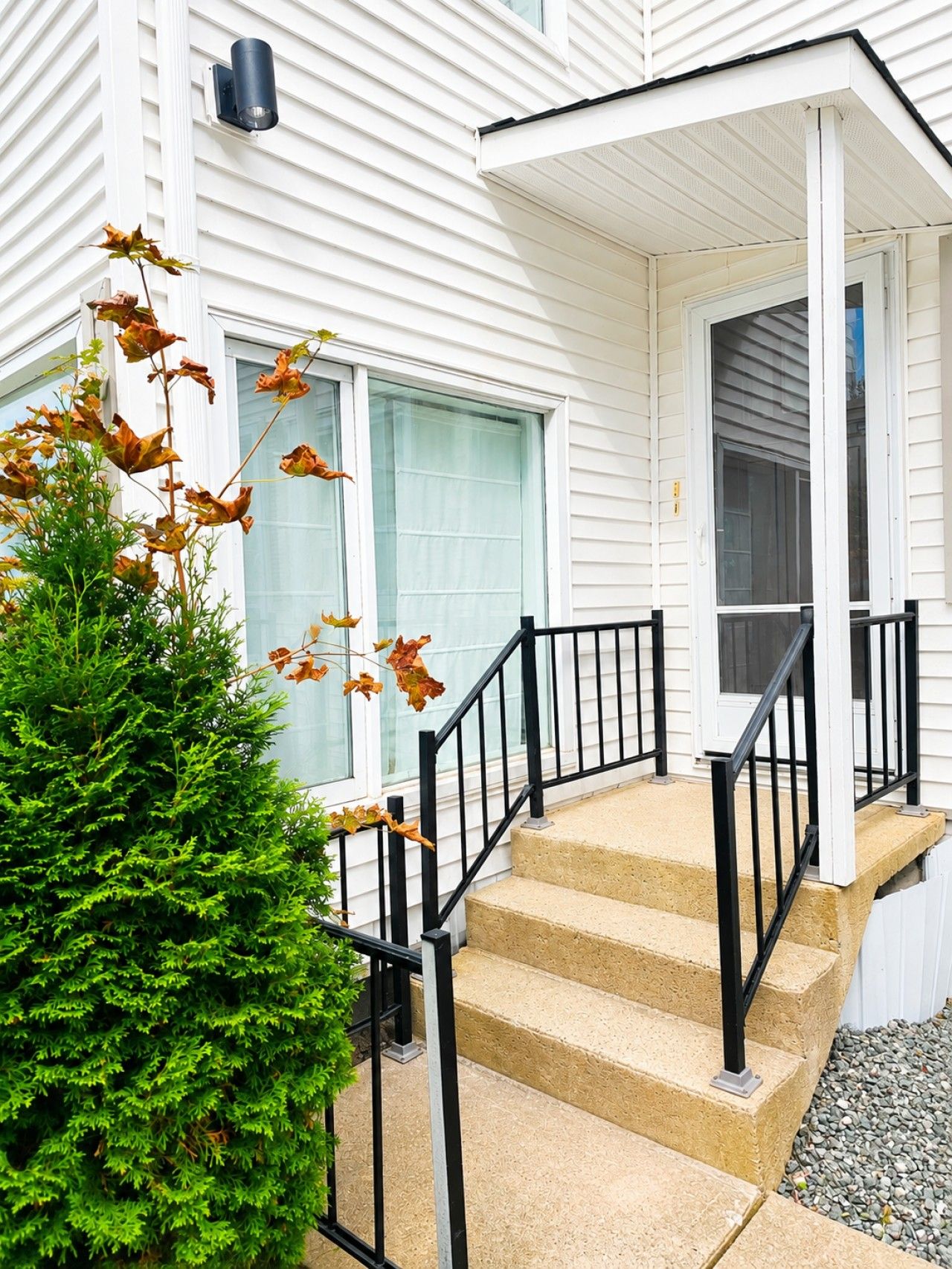 A house with a front porch, a set of stairs, and a small garden area.