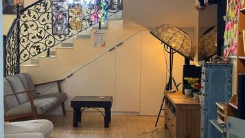 Ett vardagsrum med en trappa, en soffa, ett soffbord, en lampa och en vägg med en välkomstskylt.