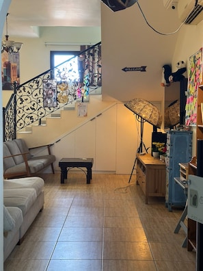 A living room with a staircase, a sofa, a coffee table, a lamp, and a wall with a welcome sign.