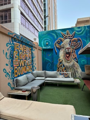 An outdoor seating area with a mural, a sofa, and a table.