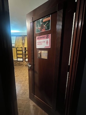 A hotel room door with a sign indicating it is a ladies' room, a no entry sign, and a picture of a room with a bed and curtains. - The Villa Hostel By Lunar (Abu Dhabi)