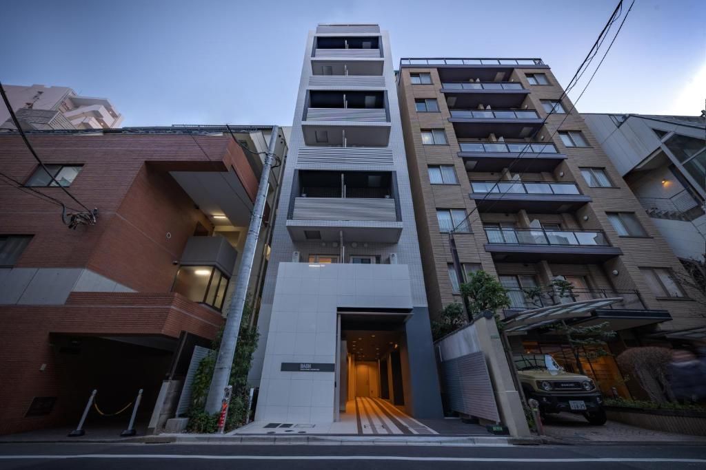 A multi-story residential building with a central entrance, balconies, and a garage with a vehicle parked outside.