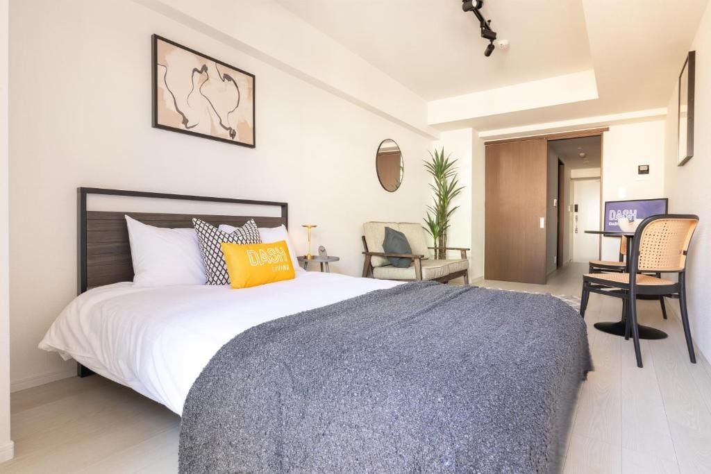 A bedroom with a bed, a desk, a chair, and a television.