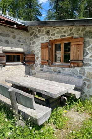 A stone building with wooden shutters and a picnic table.