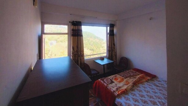 Una habitación con cama, escritorio, silla y ventana con cortinas.
