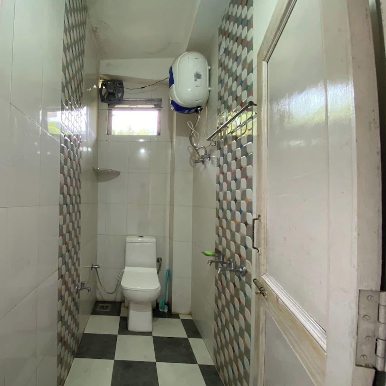 A small bathroom with a toilet, a shower, and a hand dryer mounted on the wall.