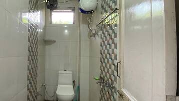 A small bathroom with a toilet, a shower, and a hand dryer mounted on the wall.