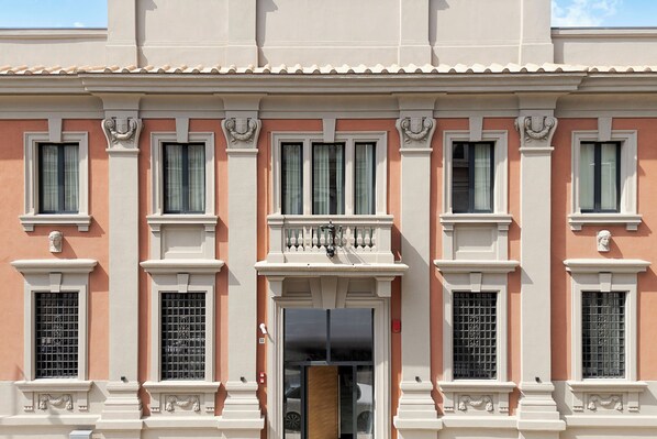 A building facade with a symmetrical window arrangement, decorative moldings, and a central entrance.