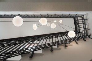A modern interior with a metal staircase and hanging spherical light fixtures.