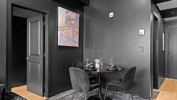 A modern dining area with a black wall, a painting of Paris, and a table set with dinnerware.