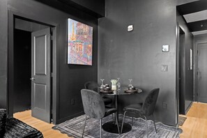 Zona pranzo moderna con una parete nera, un quadro di Parigi e un tavolo apparecchiato per cena.