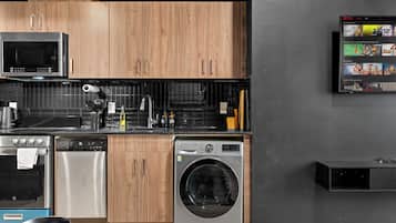 A modern kitchen with wooden cabinets, a microwave, a dishwasher, and a washing machine.