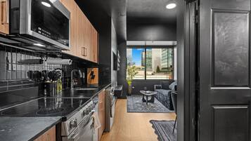 A modern kitchen with black countertops, stainless steel appliances, and wooden cabinets.