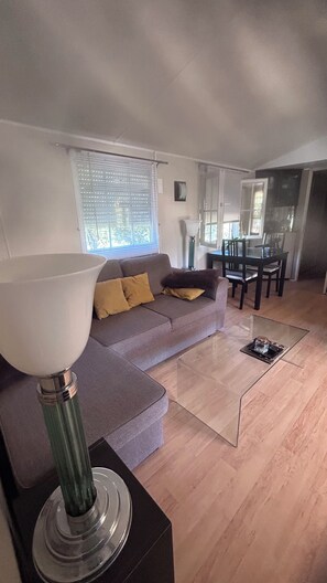 A modern living room with a sofa, a coffee table, and a dining area with chairs and a table. - A gorgeous, fully equipped motorhome (Sainte-Maxime)