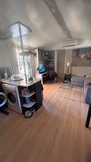 A living room with a television, a sofa, a coffee table, and a washing machine. - A gorgeous, fully equipped motorhome (Sainte-Maxime)