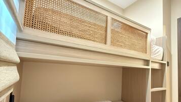 A bunk bed with a woven headboard, a bedside table, and a wall-mounted shelf.