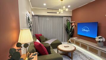 A modern living room with a sofa, a coffee table, a TV, and a lamp.