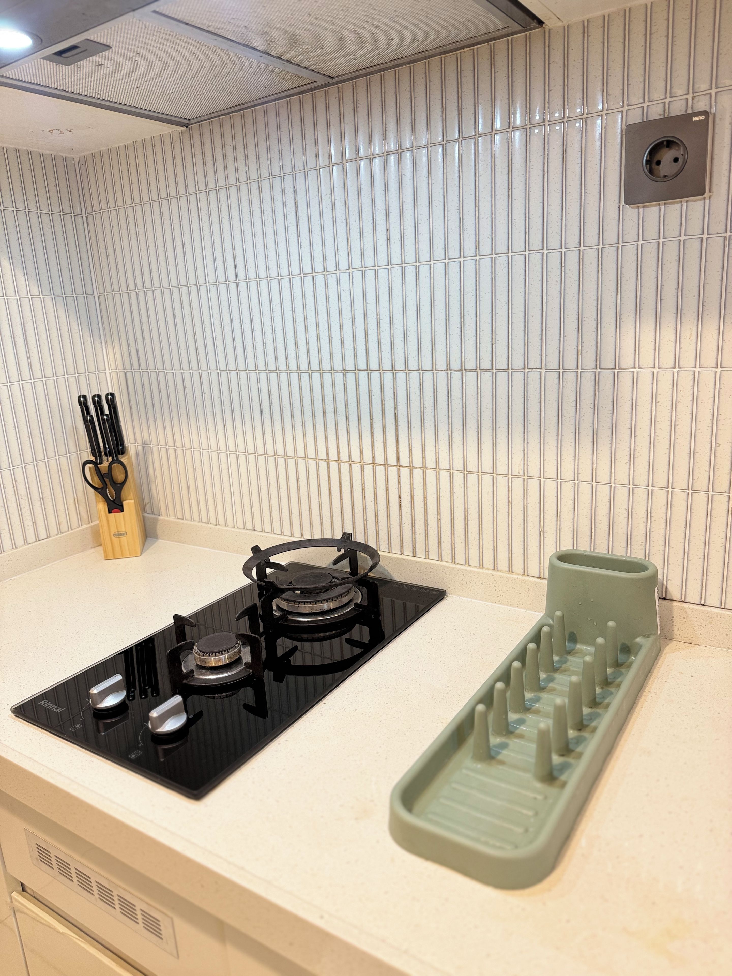 A kitchen with a gas stove, a sink, and a green dish rack.