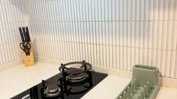 A kitchen with a gas stove, a sink, and a green dish rack.