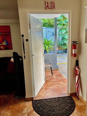 An open door leading to a patio area with a fire extinguisher on the wall and a chair outside. - Cozy Apt 1. Near the Beach, Airport, and More. All Set for a Hassle-Free Vacation (Carolina)