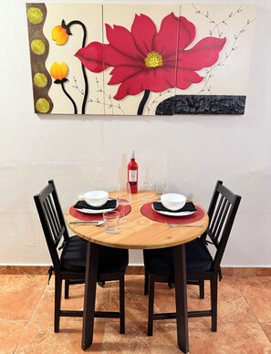 A dining table set with plates, glasses, and cutlery, chairs, and a wall-mounted artwork. - Cozy Apt 1. Near the Beach, Airport, and More. All Set for a Hassle-Free Vacation (Carolina)