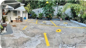 A parking area with directional arrows and a covered seating area with chairs and potted plants. - Cozy Apt 1. Near the Beach, Airport, and More. All Set for a Hassle-Free Vacation (Carolina)