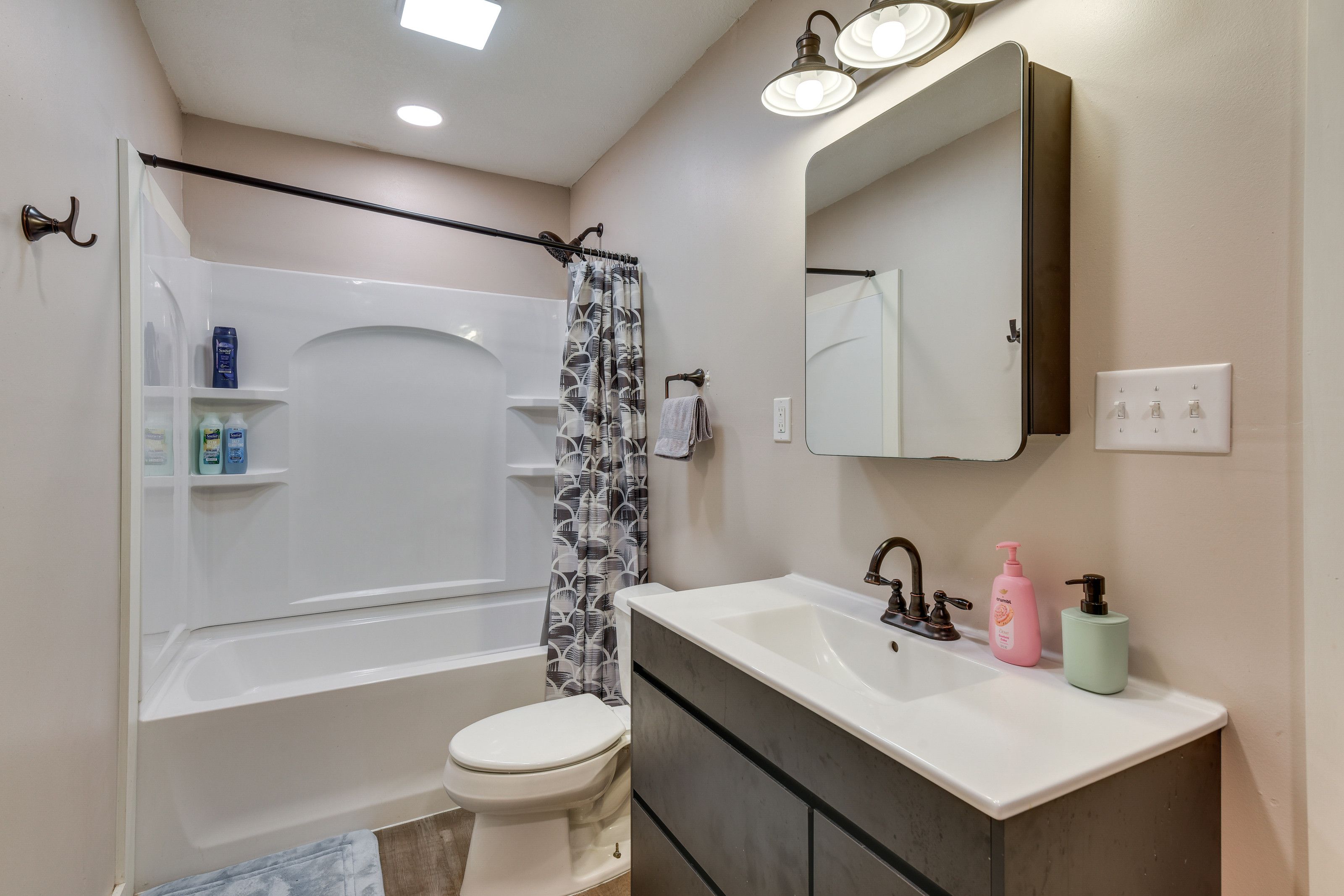 Une salle de bain équipée d’une baignoire, de toilettes, d’un meuble-lavabo avec un miroir et d’un rideau de douche.