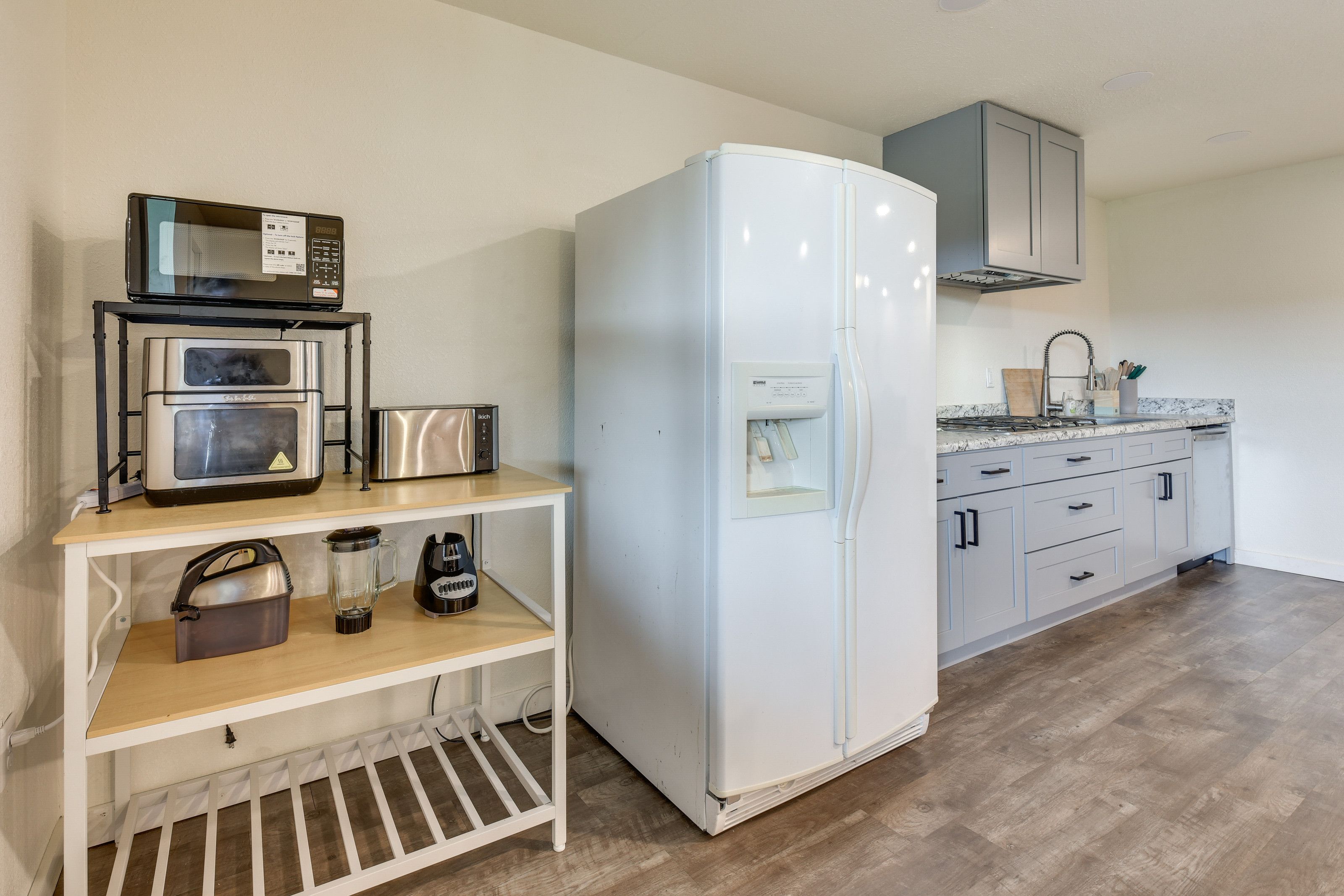 Una cocina compacta con un refrigerador blanco, un microondas, un tostador y una cafetera sobre una repisa de madera.