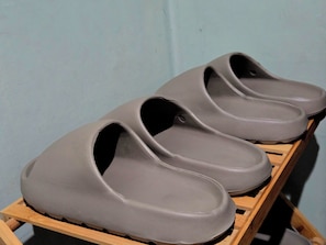 Un par de pantuflas grises sobre un estante de madera.