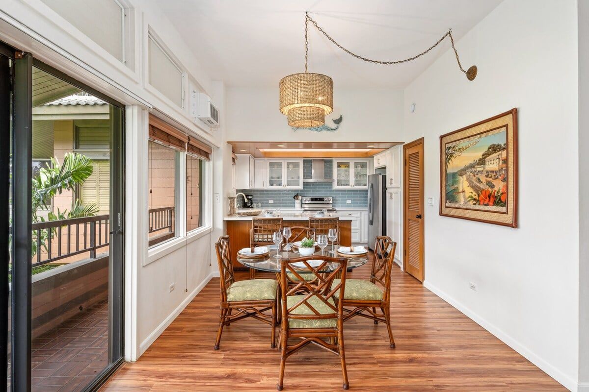 A dining area with a round table, chairs, and a hanging light fixture.