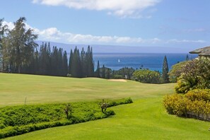 A golf course with a view of the ocean and a clear sky. - Ocean-view 1BR Kapalua condo with balcony, pool, AC, and full kitchen-Kapalua Ridge Villas 2521 (Lahaina)
