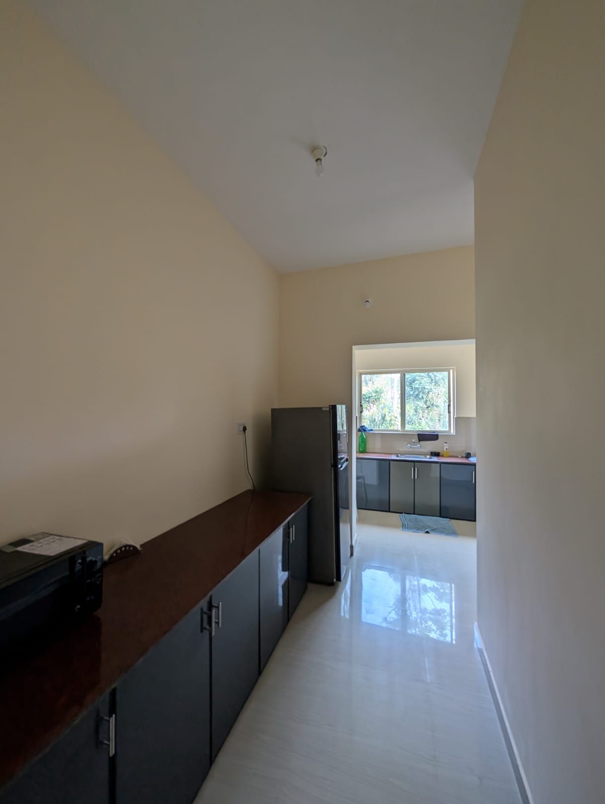 Una cocina con refrigerador, gabinetes y ventana.